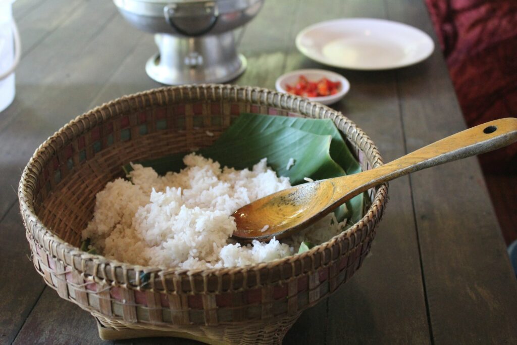 A wooden table topped with a bowl filled with rice